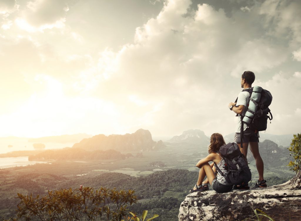 Hikers Hikers with backpacks enjoying valley view from top of a mountain
